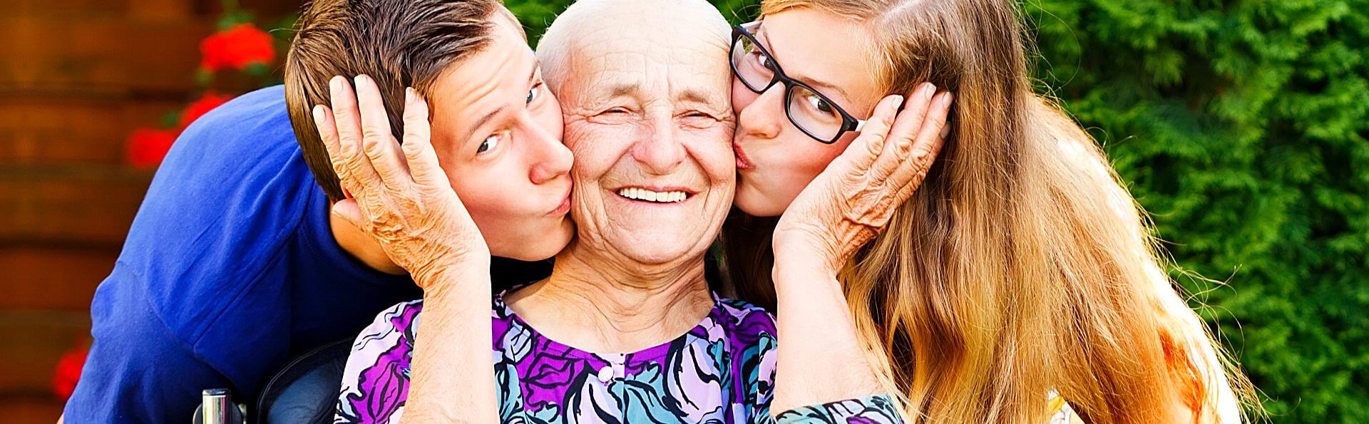 two teenagers kissing their happy grandmother